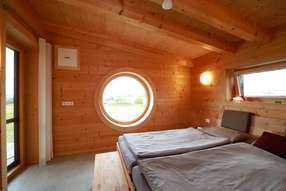 Massivholzschlafzimmer mit rundem Fenster 
